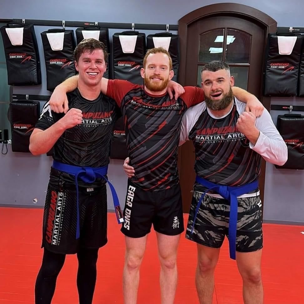 Three Jiu Jitsu fighters holding each other